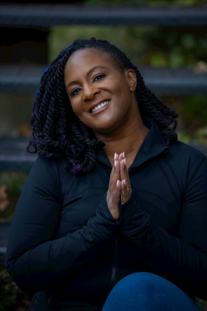 Dianne Bondy smiles at the camera with hands in namaste.