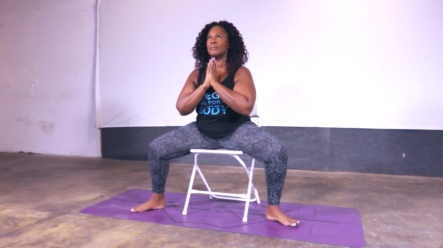 Dianne demonstrates goddess pose with a chair.