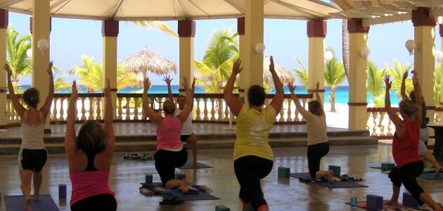Class in low lunge with a tropical sea in the distance.