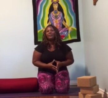 Dianne kneels on a mat with yoga props.